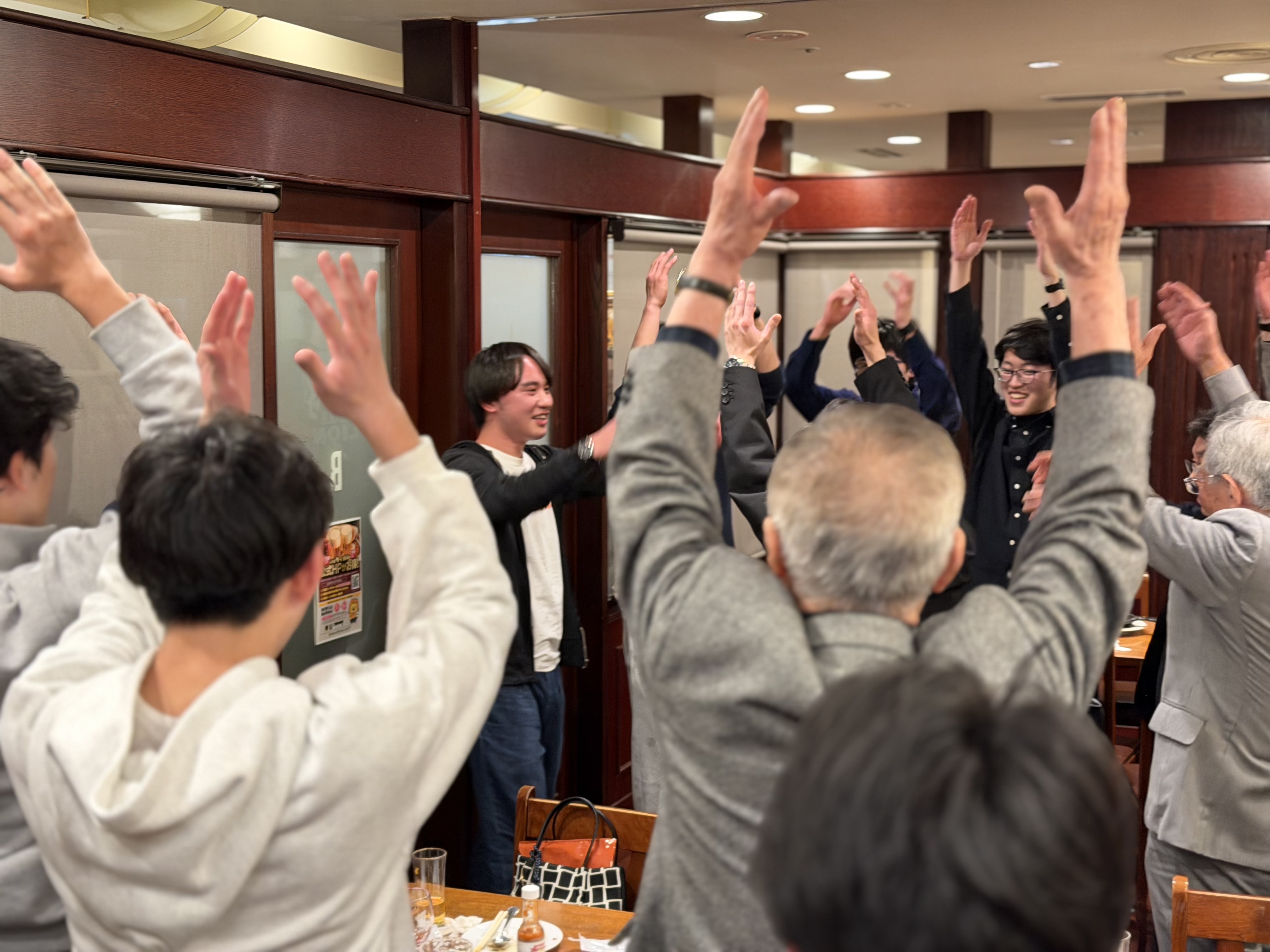 全員で手を挙げ、卒寮生の門出を盛大に祝う締めの場面