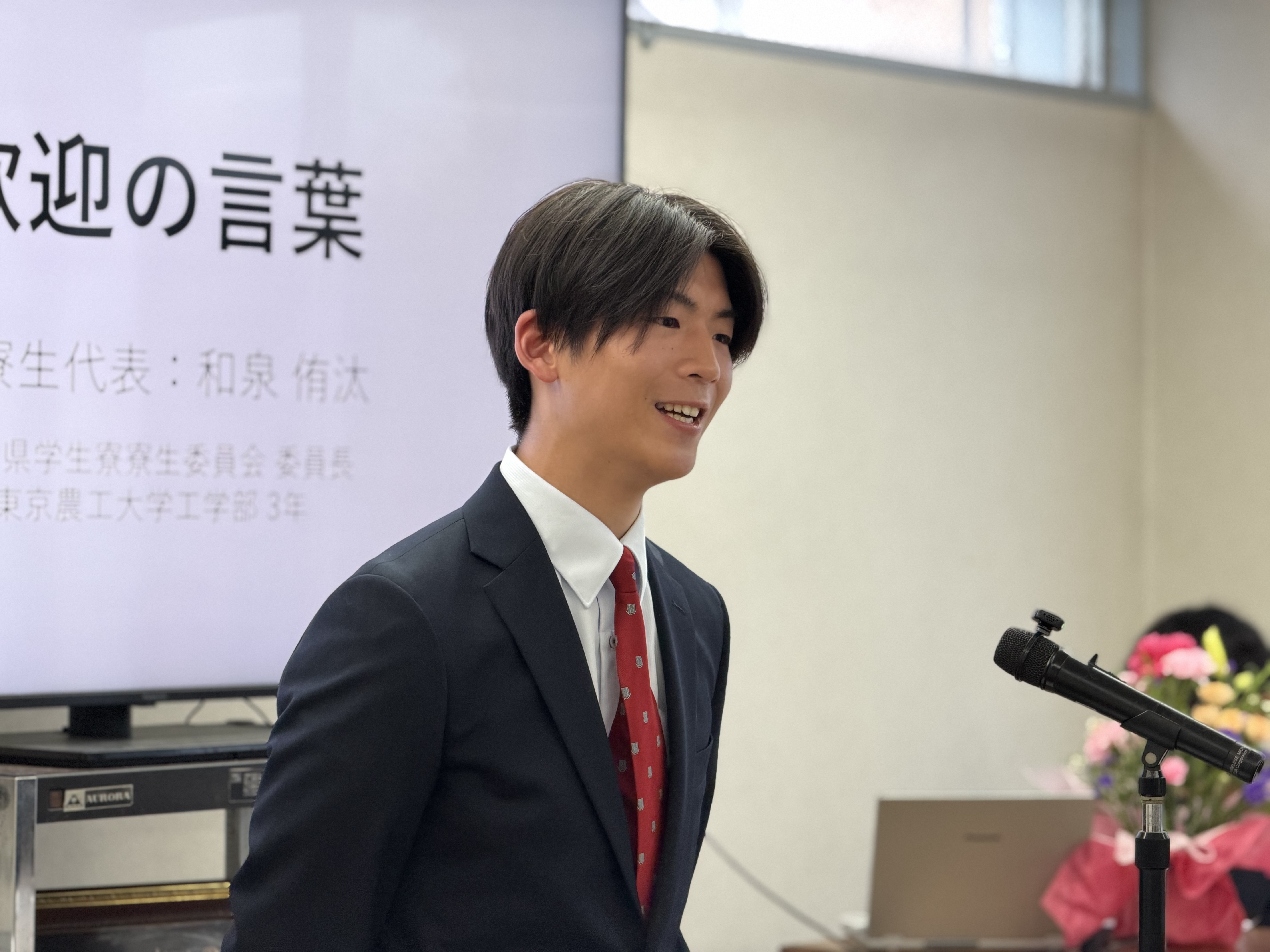 在寮生代表が歓迎の言葉を述べる様子