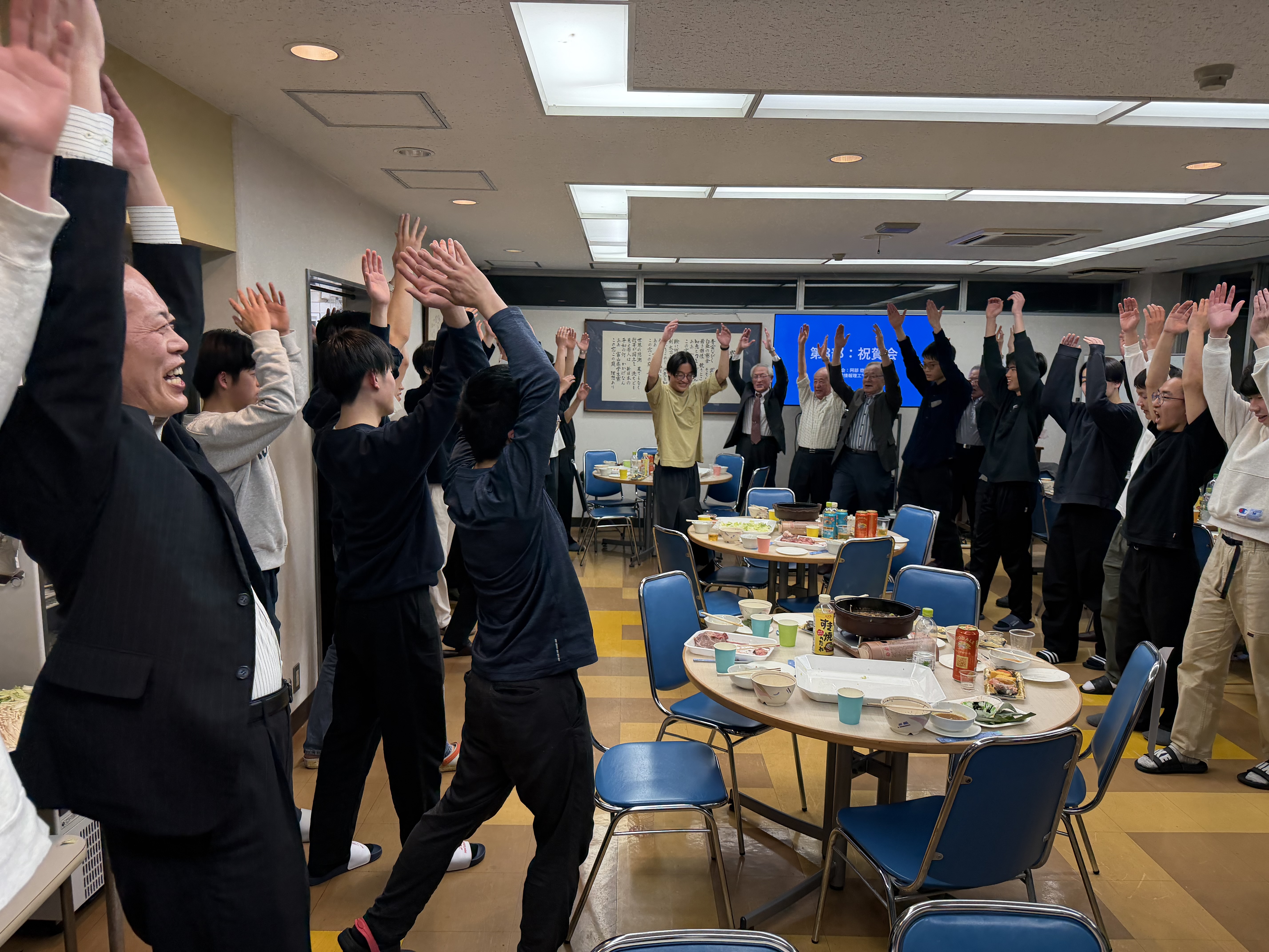 祝賀会の終盤に参加者全員で万歳三唱を行う様子