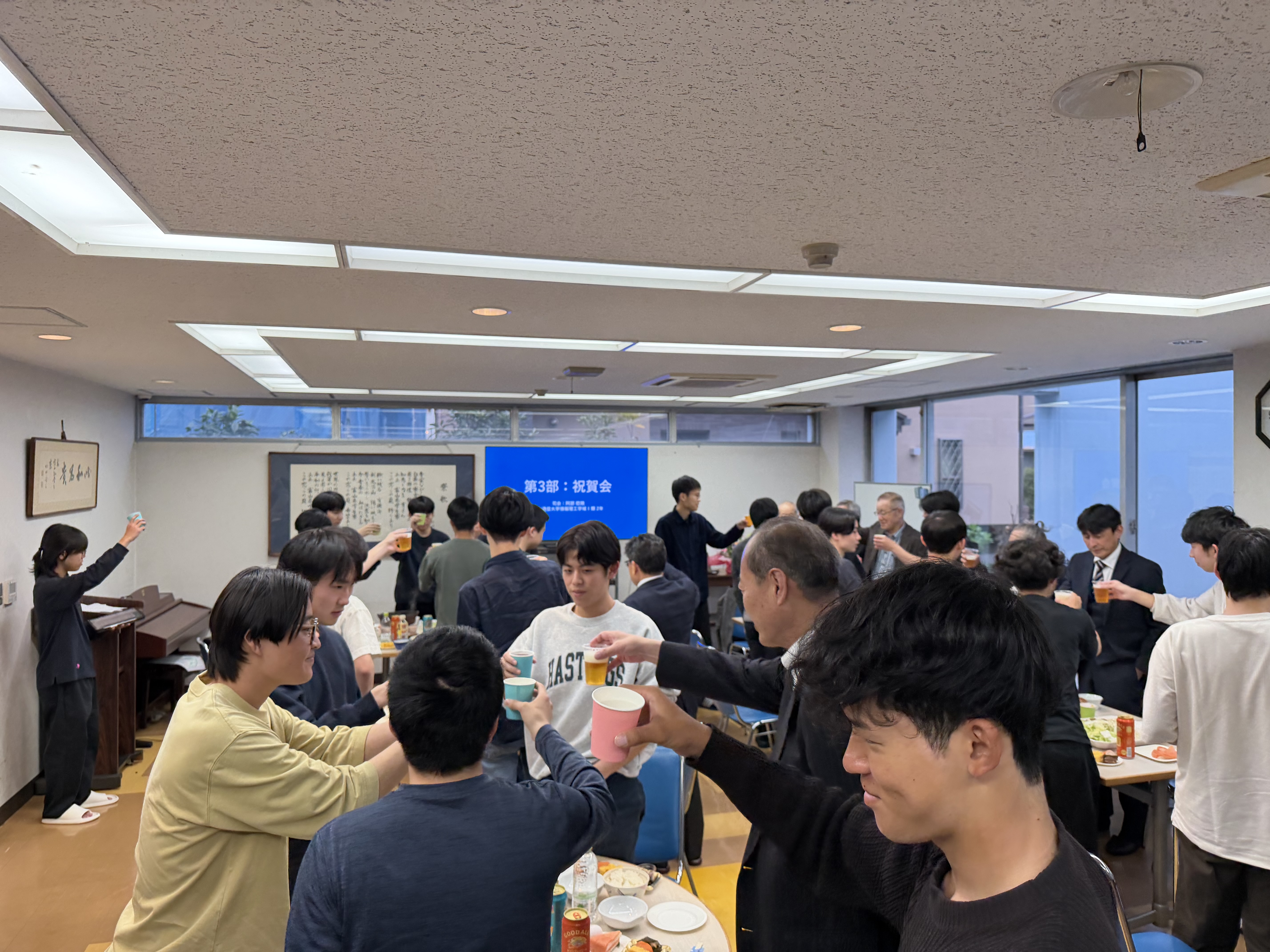 新入寮生と来賓、在寮生が食堂で乾杯する様子